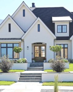 Here's an alt tag for the image: Modern white farmhouse with black trim.